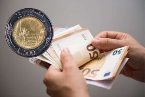 una persona che tiene in mano tanti soldi e vicino una moneta da 500 lire