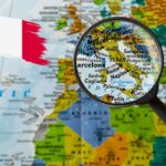 Una cartina con una lente di ingrandimento sull'Italia ed una bandiera italiana in alto a sinistra