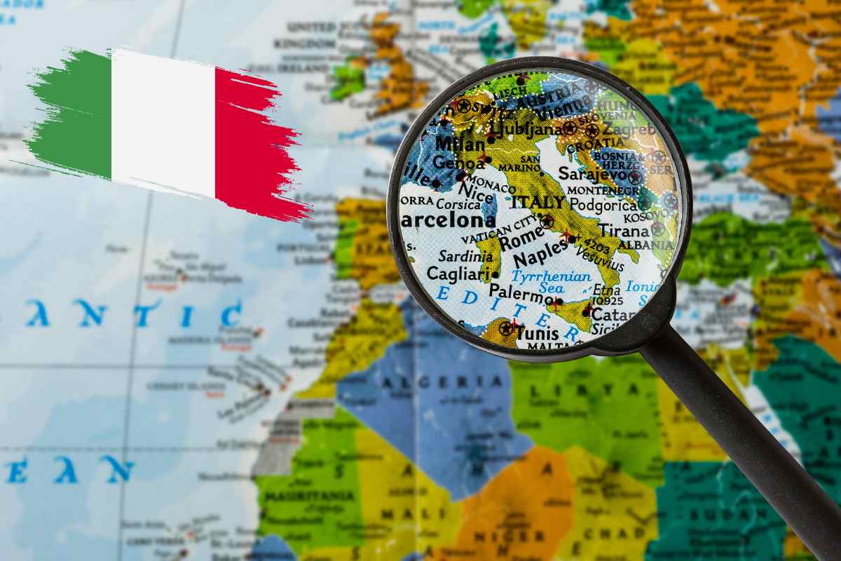 Una cartina con una lente di ingrandimento sull'Italia ed una bandiera italiana in alto a sinistra