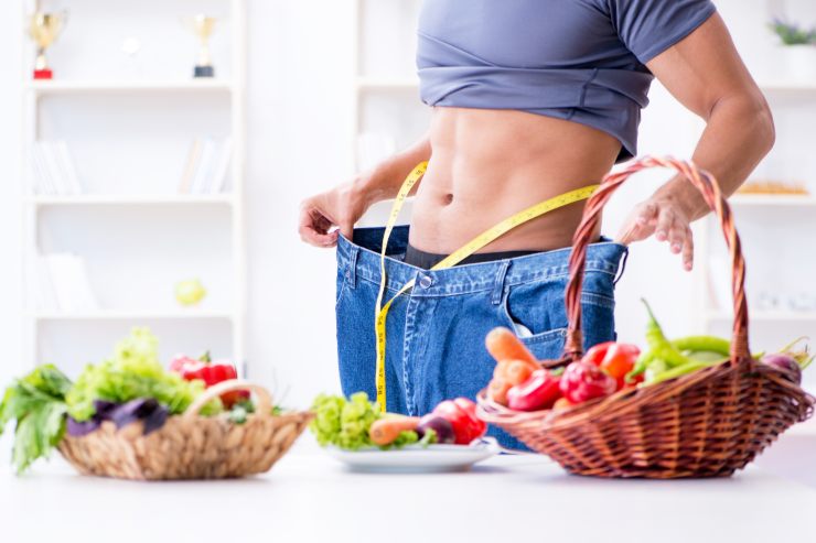 Una persona in forma che indossa dei pantaloni più grandi con un tavolo con verdura