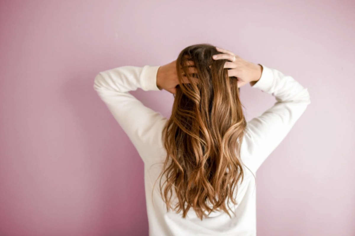 donna di spalle che si tocca i capelli lunghi