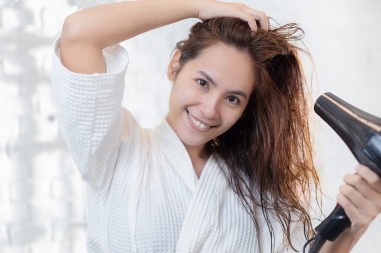 Una persona che si sta asciugando i capelli con un phon