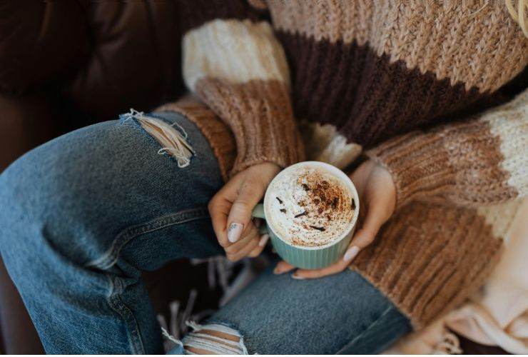 una ragazza che tiene in mano una cioccolata con la panna