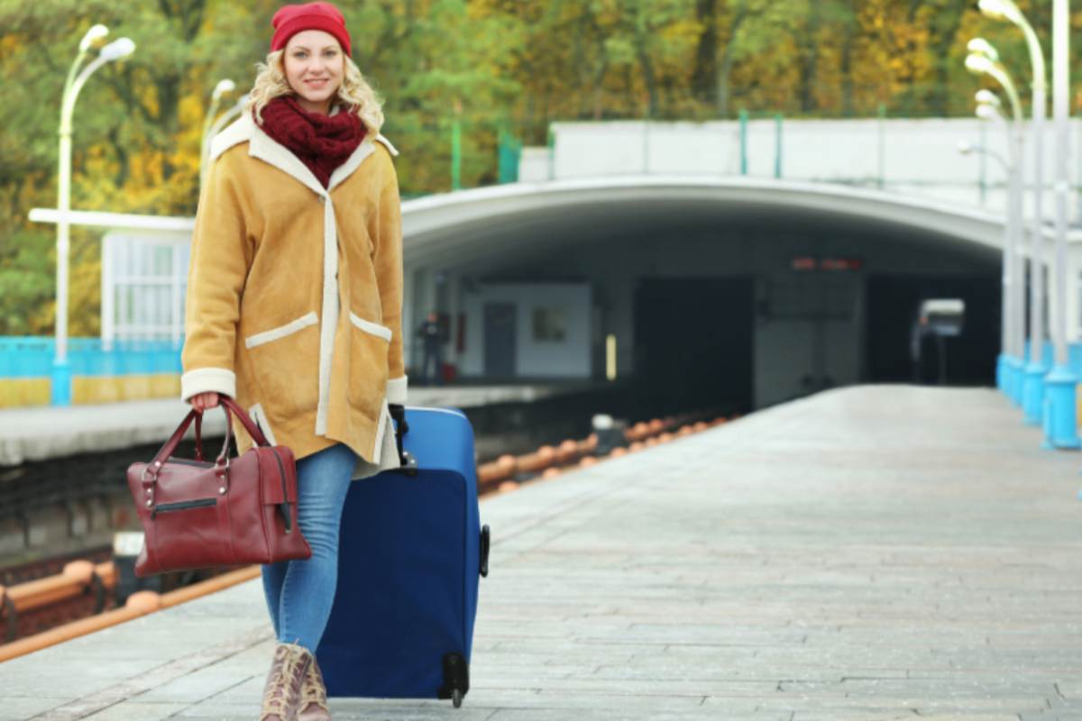 donna sorridente con un trolley e un borsone