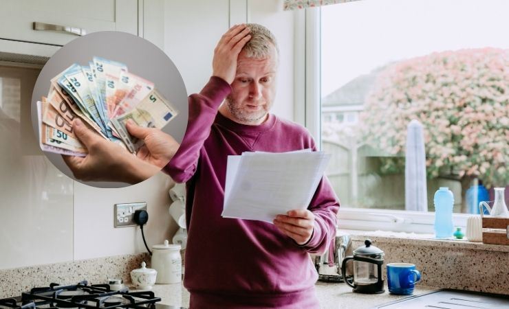 un uomo che sta leggendo una bolletta e dei soldi vicino