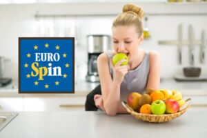 donna appoggiata sul bancone della cucina che mangia una mela