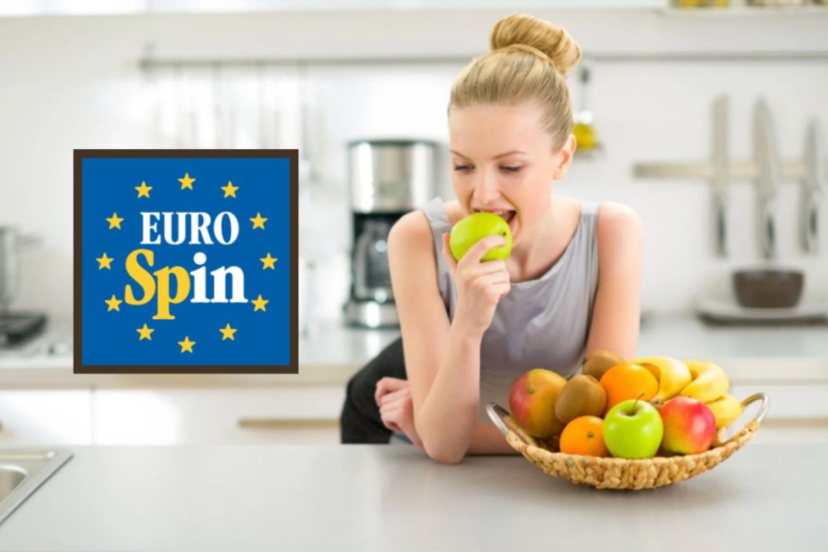 donna appoggiata sul bancone della cucina che mangia una mela