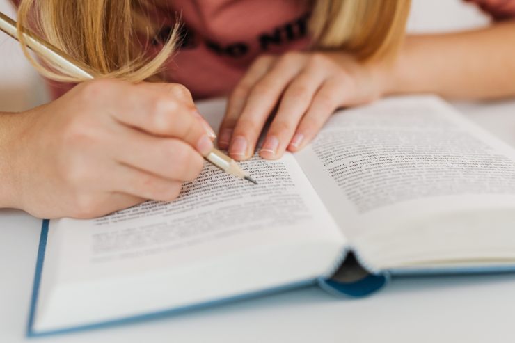 Una ragazza che sottolinea un libro mentre sta leggendo