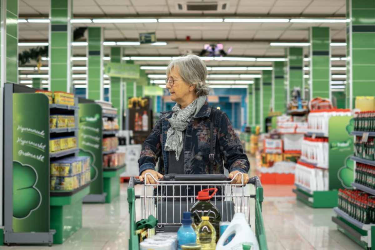 donna anziana al supermercato con un carrello pieno