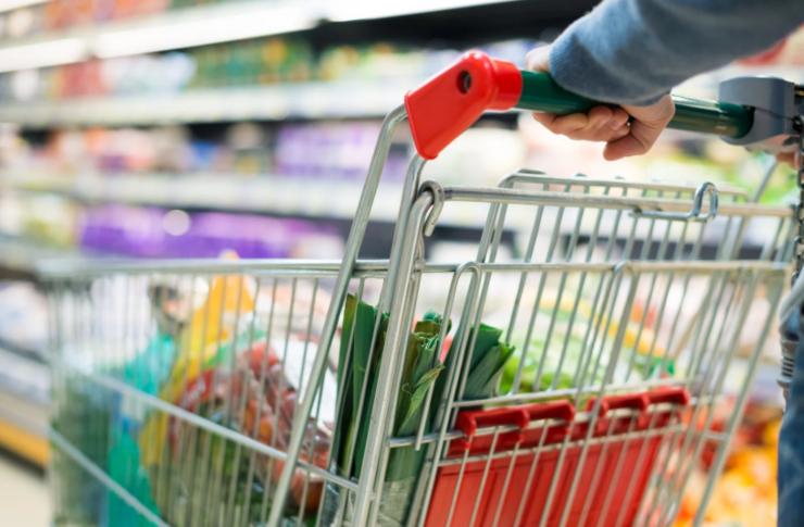 persona al supermercato che spinge un carrello pieno di cibo