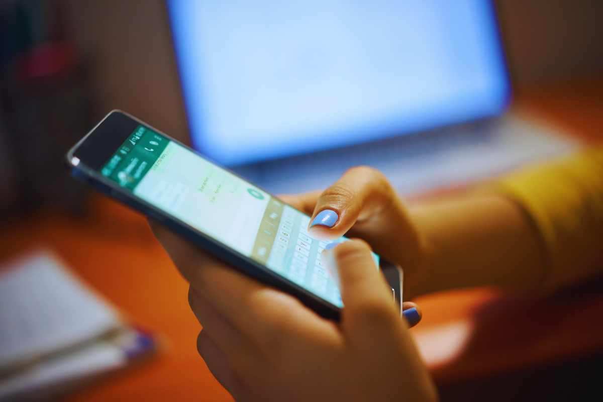 Cellulare tenuto tra le mani con una mano che digita