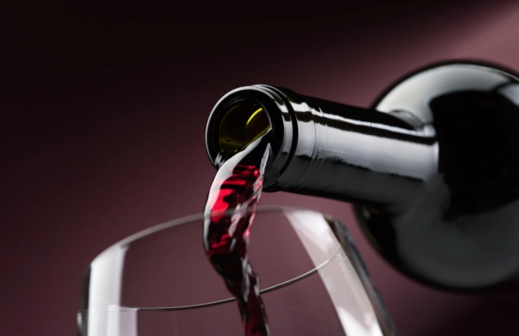 persona che versa del vino rosso dentro ad un calice