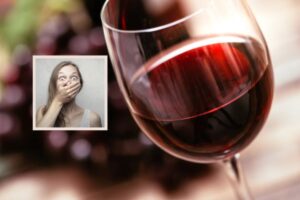 calice di vino rosso e donna scioccata con una mano sulla bocca