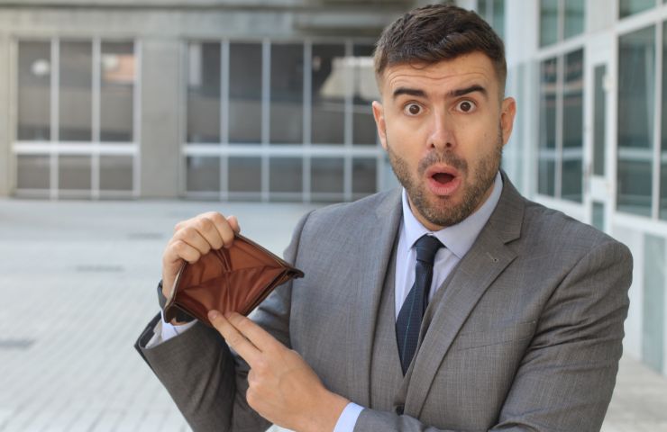 uomo sconvolto con portafoglio vuoto