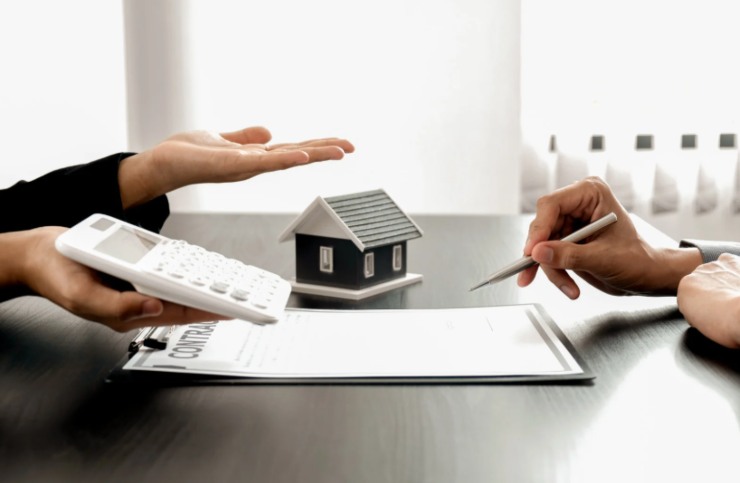 persona che firma un contratto di affitto e un'altra persona con la calcolatrice in mano