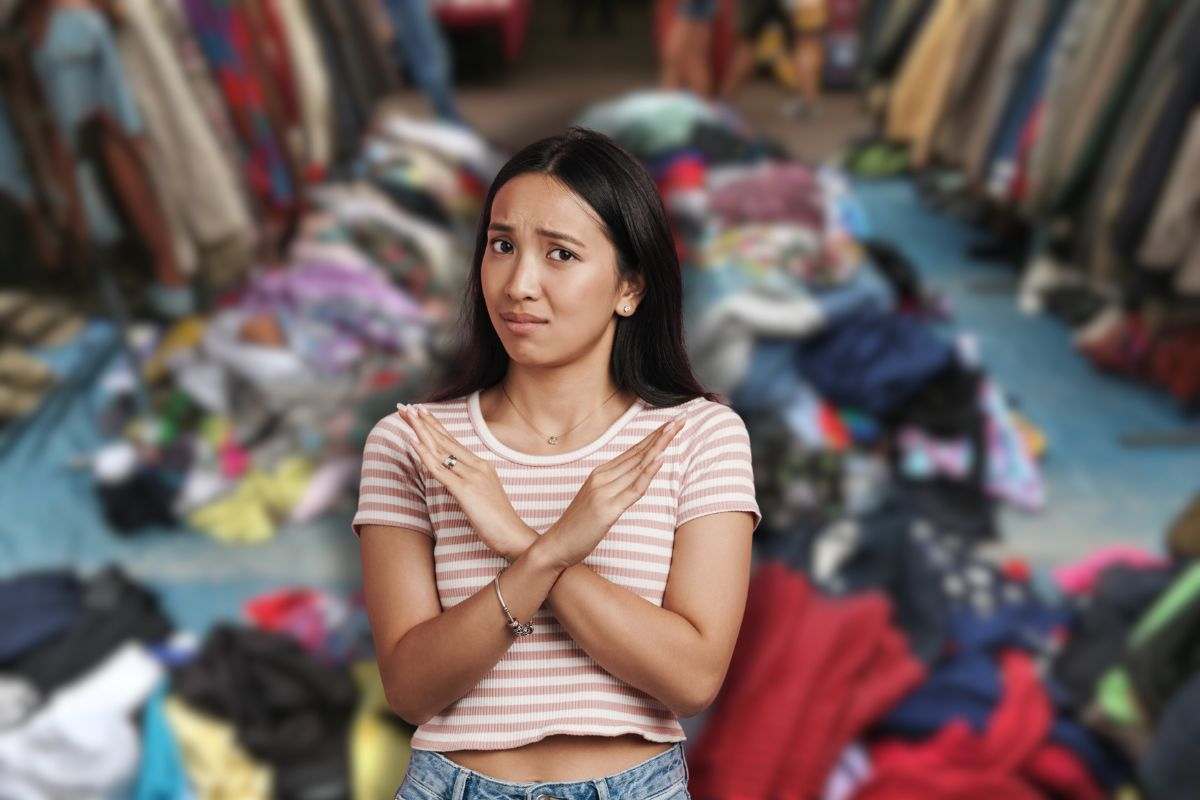 vestiti nel mercatino dell'usato e donna che fa stop con le mani