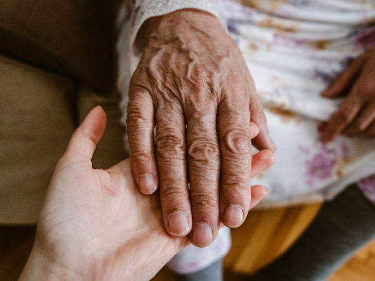 mano di una persona anziana sorretta da un'altra mano