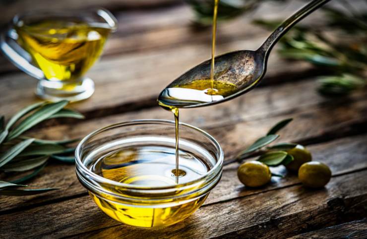 persona che versa dell'olio dentro ad una ciotolina di vetro 