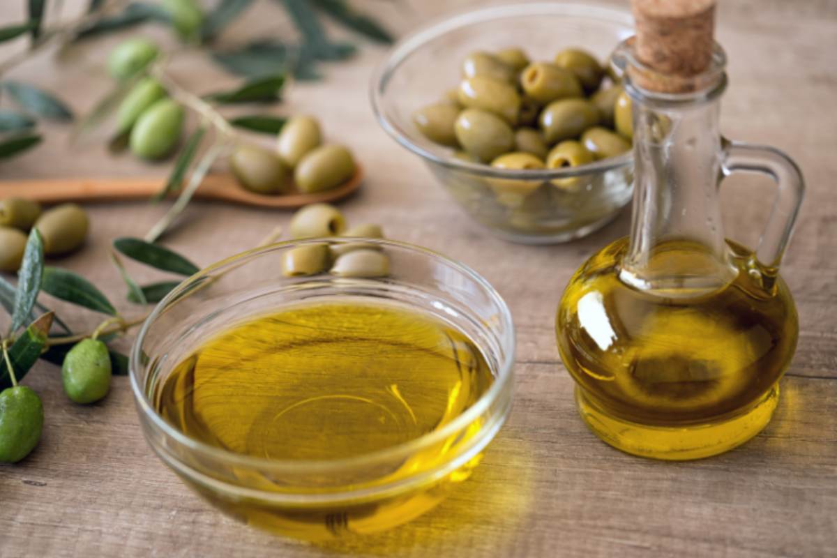 olio di oliva e accanto delle olive verdi