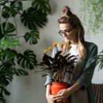 donna con una pianta in mano e altre piante intorno