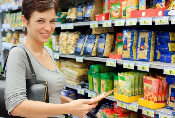 donna sorridente al supermercato che sceglie pasta 