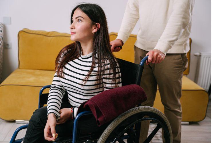 una ragazza sulla sedia a rotelle e una persona che l'aiuta