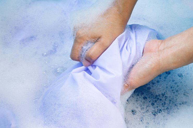 Una persona che lava a mano dei vestiti