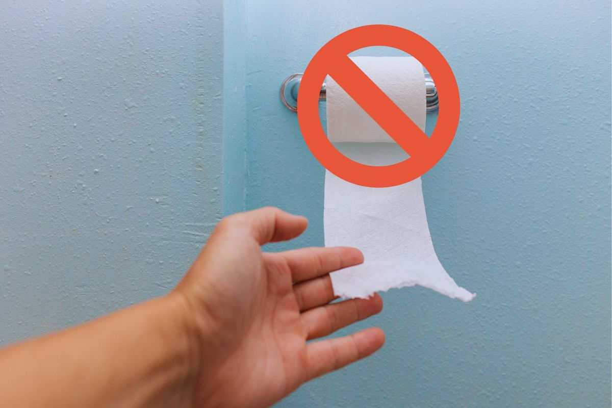 Uomo che cerca di prendere carta igienica sbarrata da simbolo di divieto