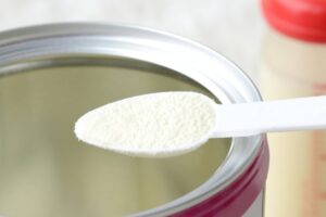 cucchiaio con latte in polvere e barattolo