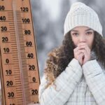 Donna che si riscalda le mani, con cappello, freddolosa. Termometro