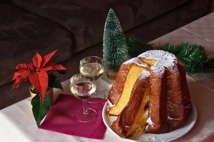 Pandoro alcune fette tagliate nel tavolo da portata, due calici di spumante, tavola addobbata a festa 