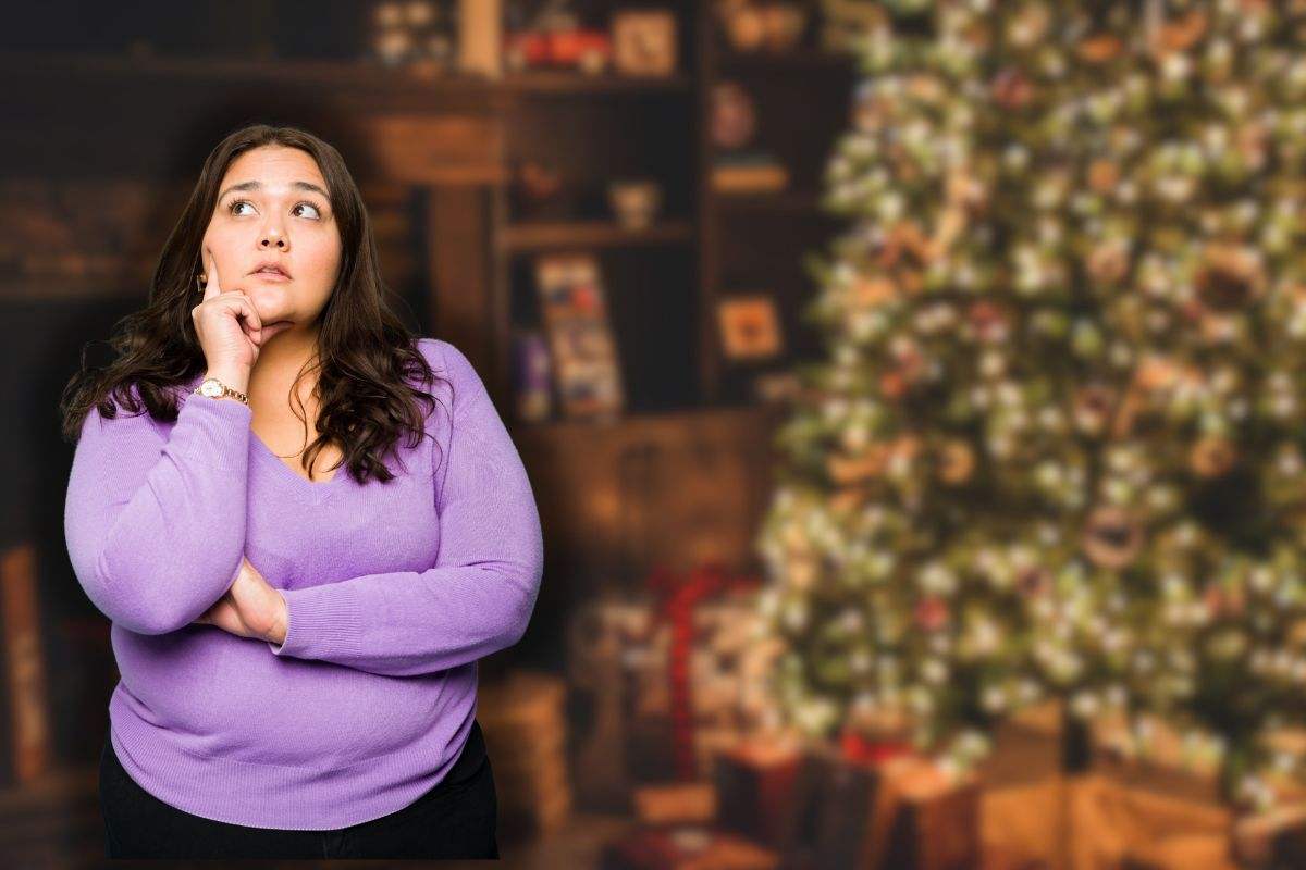 albero di natale addobbato con luci e donna che pensa