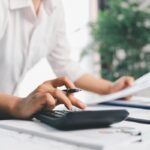 mani che digitano su calcolatrice con penna