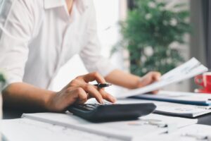 mani che digitano su calcolatrice con penna