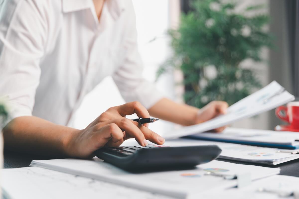 mani che digitano su calcolatrice con penna