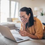 Donna con mano sulla bocca davanti al PC guarda la carta